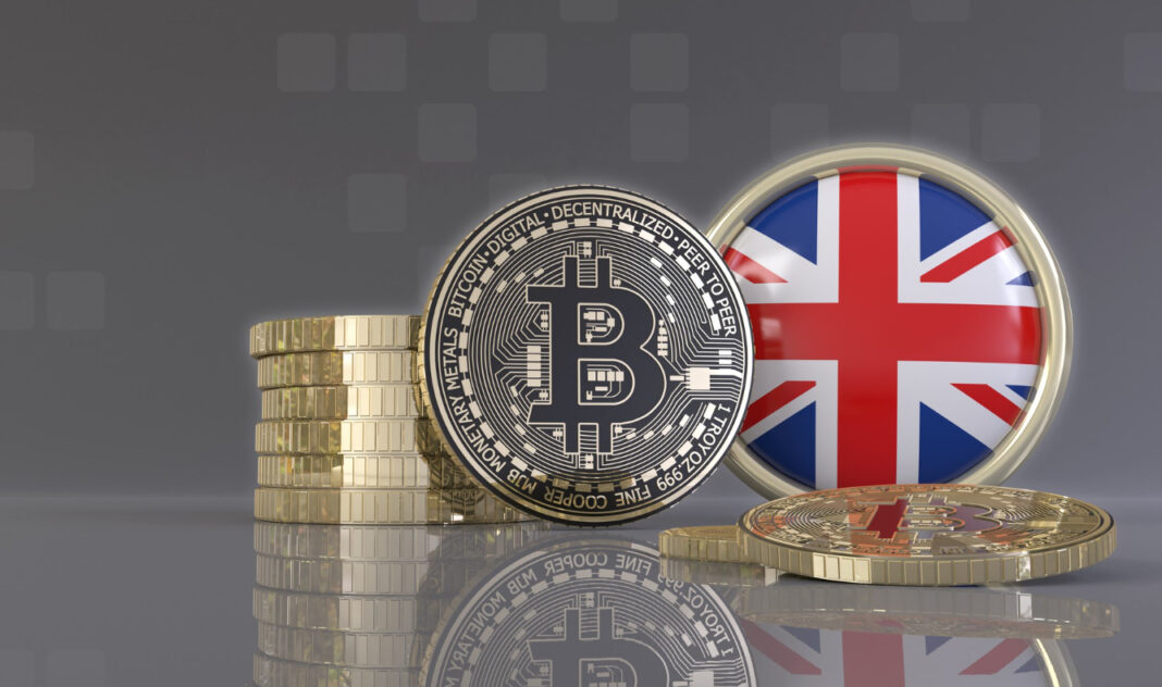 A gold physical Bitcoin and cryptocurrency token displayed against a Union Jack flag background, symbolising the UK's new digital property laws.